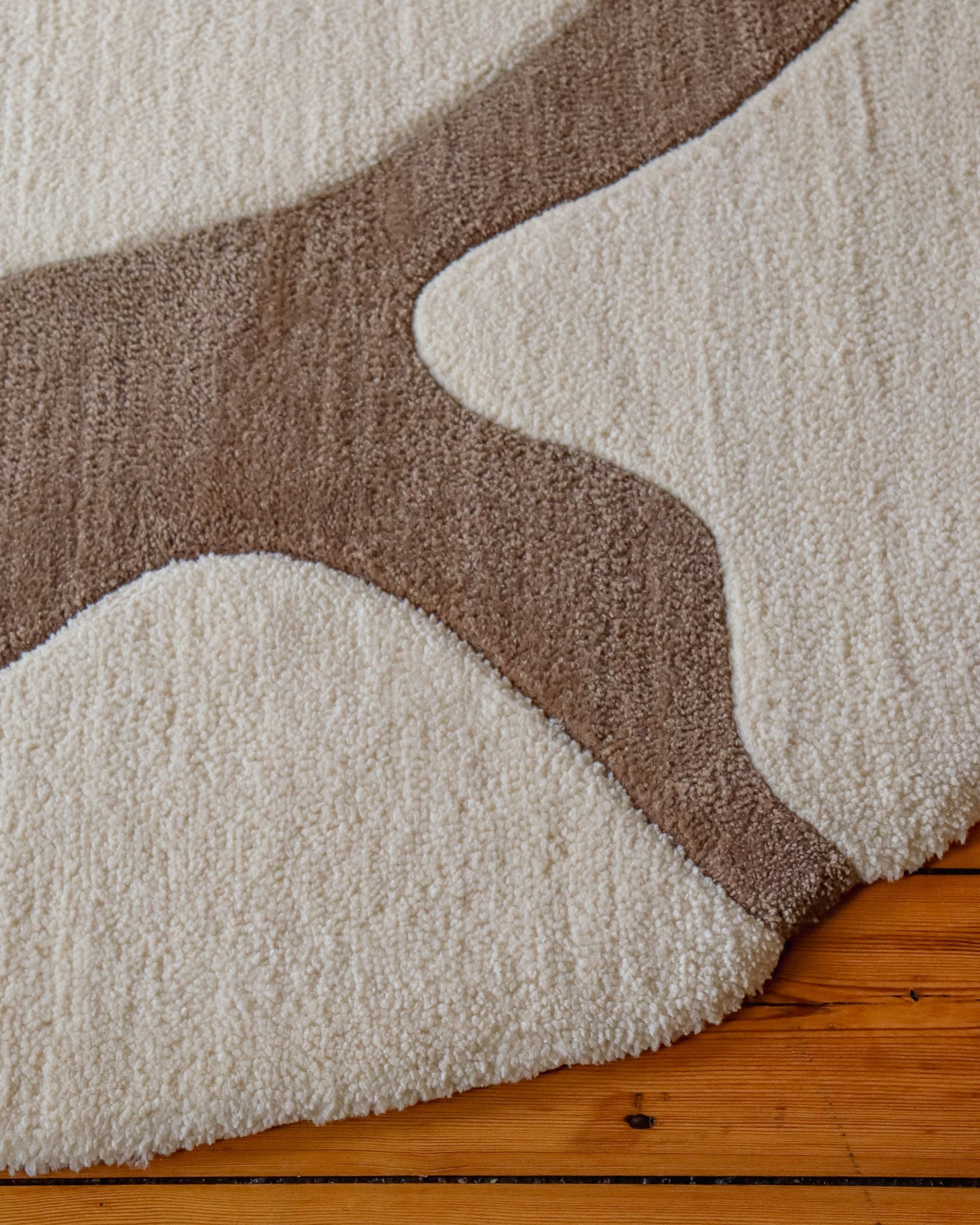 Close-up of a textured rug with wavy pattern on a wooden floor