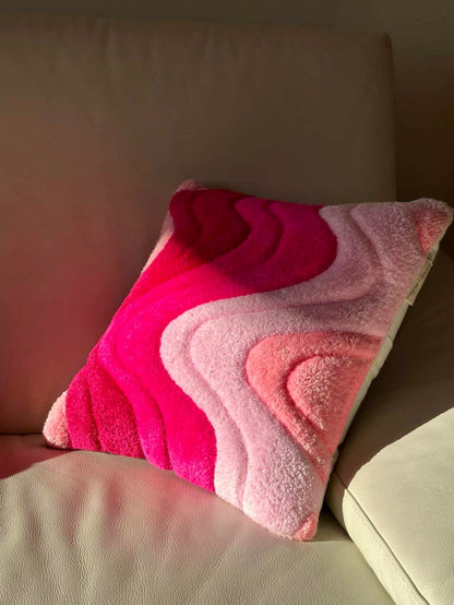 Pink and red patterned pillow on a beige couch