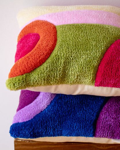 Colorful textured cushions with geometric patterns on a wooden surface.