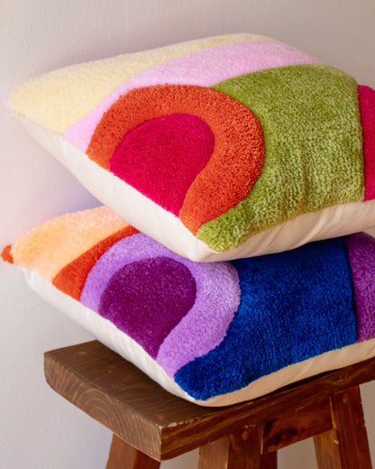 Colorful textured pillow on a wooden stool against a plain background