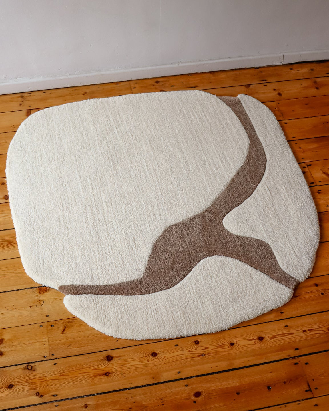 White rug with brown abstract design on a wooden floor