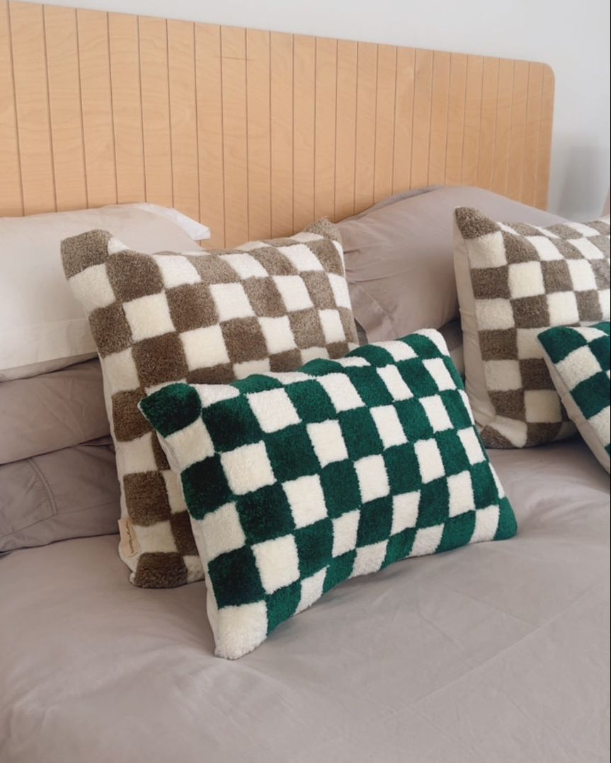 Checkered cushions on a bed with a wooden headboard