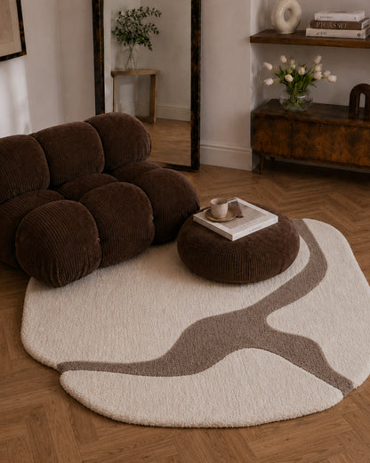 Brown sofa and ottoman on a round beige rug in a living room setting.
