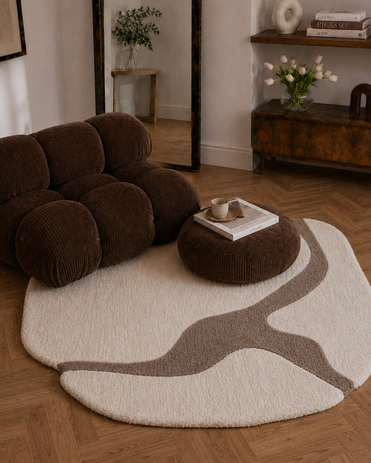 Brown sofa and ottoman on a round beige rug in a living room setting.